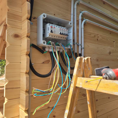 ארון חשמל פתוח עם חוטים צבעוניים וסולם עץ