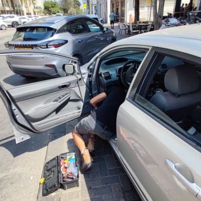 אדם מתקן רכב עם ארגז כלים פתוח