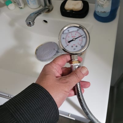 מד לחץ מים מוחזק מעל כיור בחדר אמבטיה