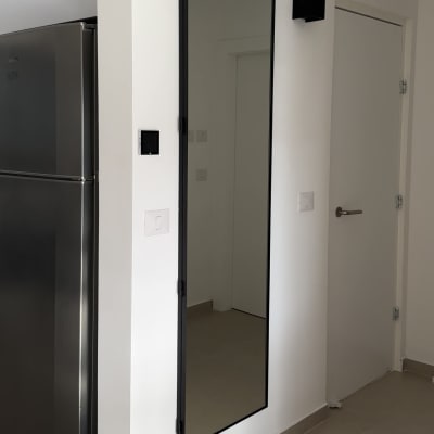 מראה תלויה על קיר ליד מקרר ודלת