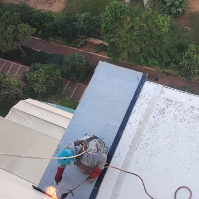 עובד בגובה עם קסדה מבצע עבודת איטום