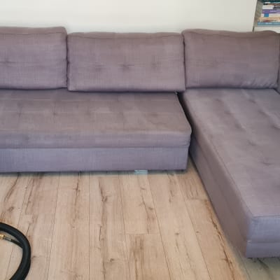 ספה אפורה עם ציוד ניקוי על רצפת עץ