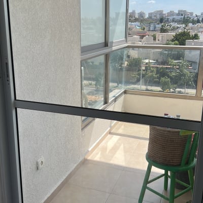 מרפסת עם כיסא ירוק ומטאטא ורוד