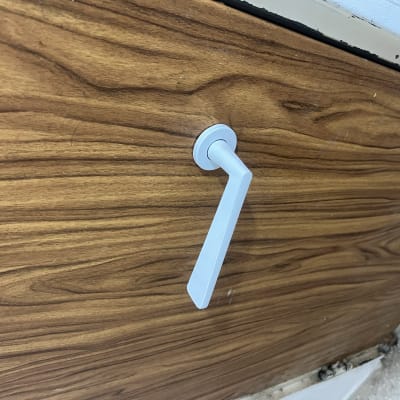 ידית דלת לבנה על דלת עץ