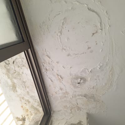 קיר עם קילופי צבע ותיקוני טיח ליד חלון