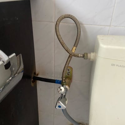 צינור מים מחובר לשסתום מתכת ליד אסלה