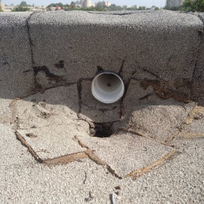 צינור פלסטיק לבן על גג עם זפת וסדקים