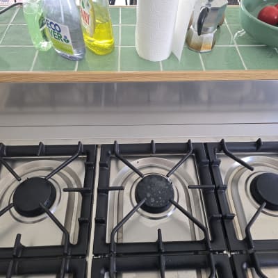 כיריים עם בקבוקי חומרי ניקוי ועגבניות בקערה ירוקה