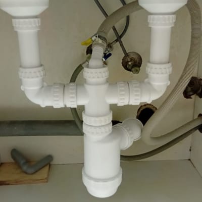 צנרת פלסטיק לבנה מתחת לכיור עם חיבורים