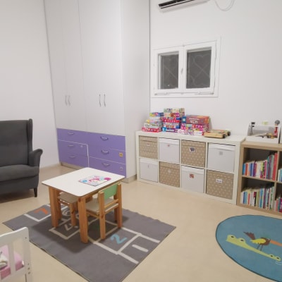 ארון לבן עם מגירות סגולות, מדפים עם קופסאות וצעצועים