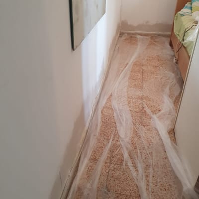 קיר צבוע חלקית עם יריעת ניילון על הרצפה