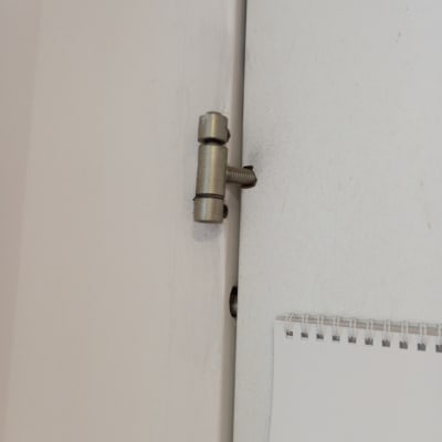 ציר מתכת מותקן על דלת לבנה