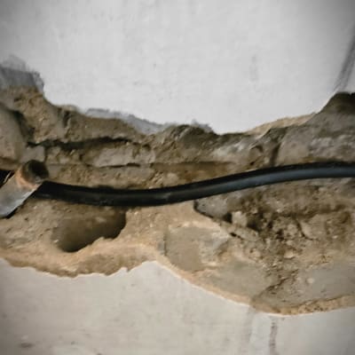 צינור שחור בקיר עם טיח חשוף