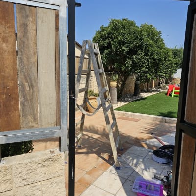 התקנת אינטרקום על עמוד מתכת ליד שער עץ