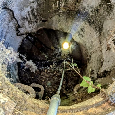 צינור מתכת נכנס לפתח ביוב עם אור בפנים