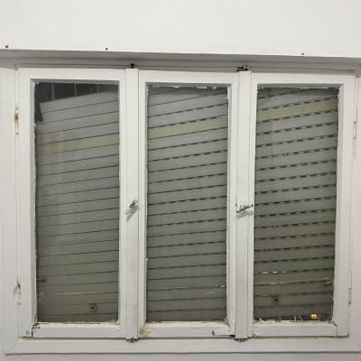 חלון עם תריסים סגורים בתוך מסגרת לבנה