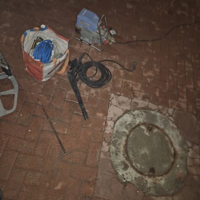 כלים וציוד ליד מכסה ביוב על רצפת לבנים