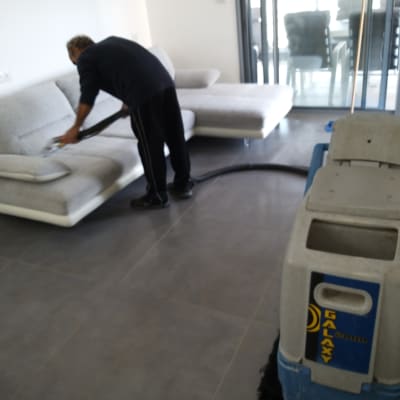 אדם מנקה ספה עם שואב אבק מקצועי
