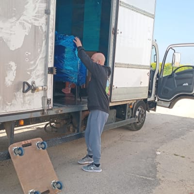 אדם מעמיס משאית עם חפצים עטופים בניילון כחול