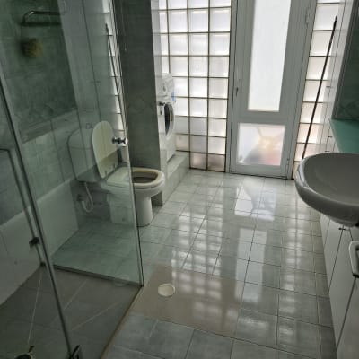 חדר אמבטיה נקי עם מקלחת, שירותים ומכונת כביסה