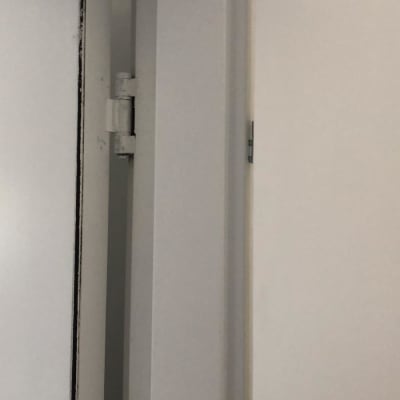 דלת לבנה עם ציר מתכת במסגרת אפורה