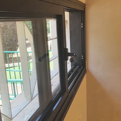 חלון אלומיניום עם מסגרת כהה וידית פתיחה