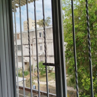 חלון עם סורגים ונוף של בניינים ועצים