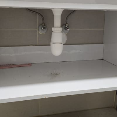 צינור ניקוז לבן מתחת לכיור עם ברזים