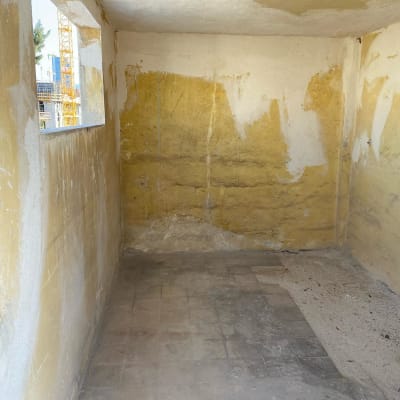חדר ריק עם קירות מתקלפים ורצפה מלוכלכת