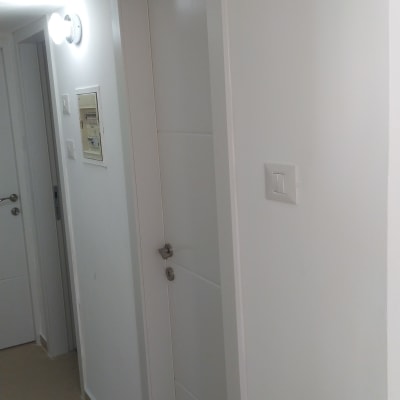 דלת לבנה עם ידית מתכת במסדרון לבן