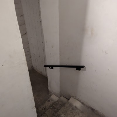 מעקה שחור מותקן על קיר ליד מדרגות בטון