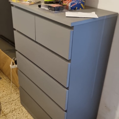 שידה אפורה עם חפצים עליונים, כולל קופסה צבעונית