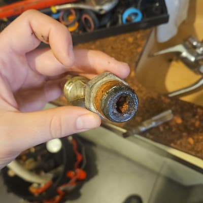 יד מחזיקה צינור חלוד עם כלים ברקע