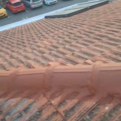 גג רעפים חום עם מכוניות חונות ברקע