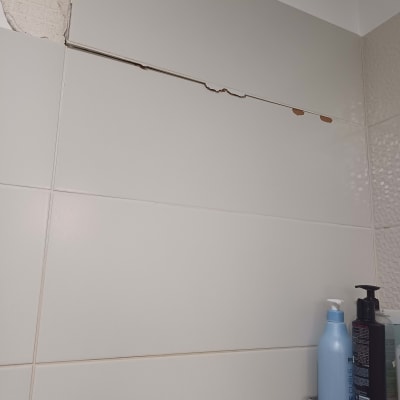 אריחים שבורים על קיר עם בקבוקי סבון