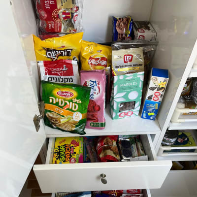 ארון מטבח עם חטיפים וממתקים מסודרים במדפים ומגירות