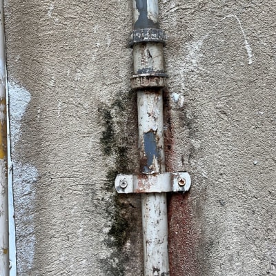 צינור מתכת חלוד מחובר לקיר בטון