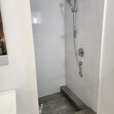 מקלחת עם אריחים לבנים וברז חדש