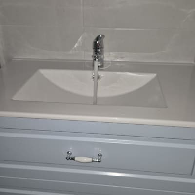 ברז מים זורם בכיור לבן עם ארון תחתון