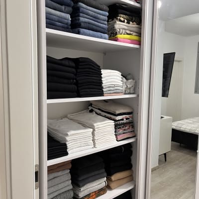 בגדים מקופלים ומסודרים בארון לבן עם מדפים