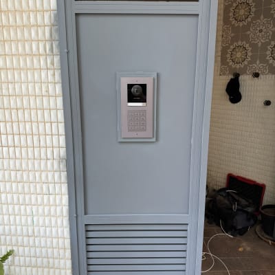 אינטרקום עם מצלמה ולוח מקשים על דלת מתכת אפורה