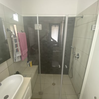 מקלחת עם דלת זכוכית, כיור ומגבות