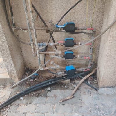 צינורות מים עם ברזים כחולים על קיר חיצוני