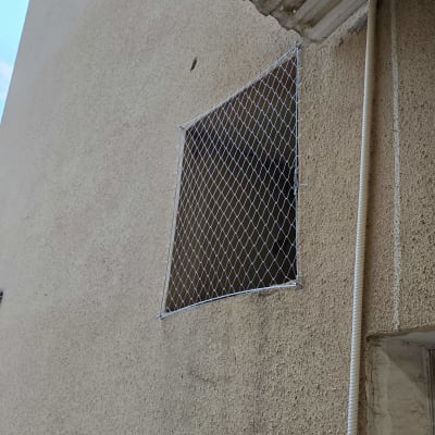 רשת מותקנת על חלון למניעת כניסת יונים