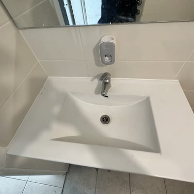 כיור לבן עם ברז מתכת ומתקן סבון