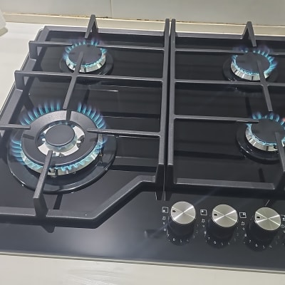 כיריים גז זכוכית שחורה מותקנות על משטח עבודה ודולקות בלהבה כחולה תקינה