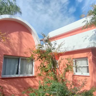 בית ורוד עם חלונות ועצים מסביב