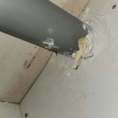 צינור אפור עם איטום לבן על קיר