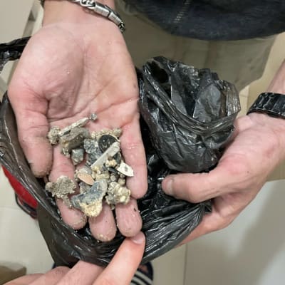 ידיים מחזיקות שברי צינורות בשקית שחורה