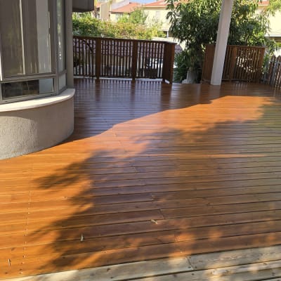 דק עץ חום עם גדר עץ וצמחייה מסביב